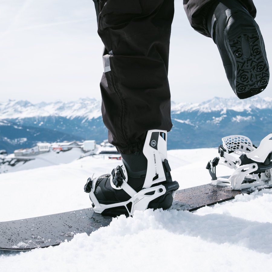 Een persoon die een paar zwart-witte snowboardbindingen draagt