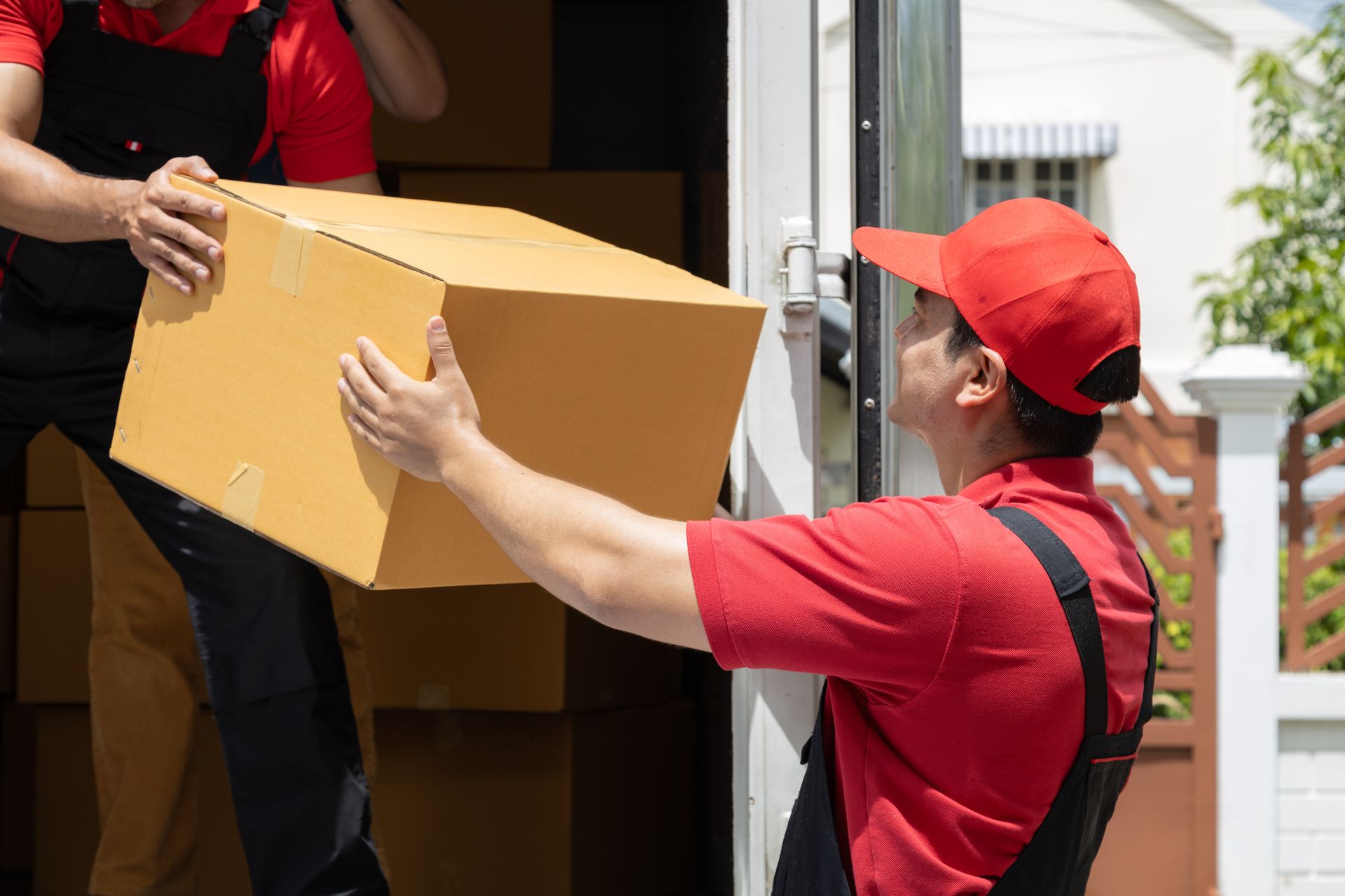 Movers in Red Unloading a Cardboard Box from A Truck — Dan's Removals In Brunswick Heads, NSW