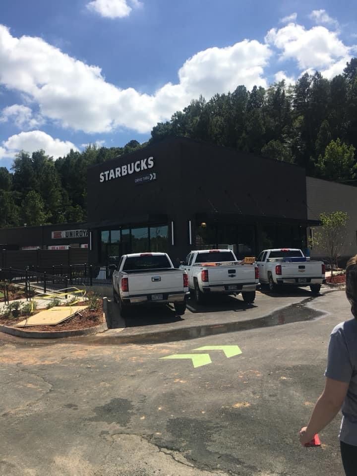 Starbucks storefront with parked trucks under a cloudy sky, viewed from a paved lot