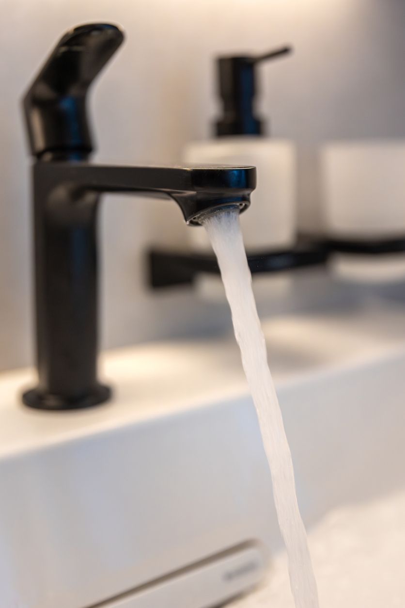 Black bathroom faucet with water running into a white sink