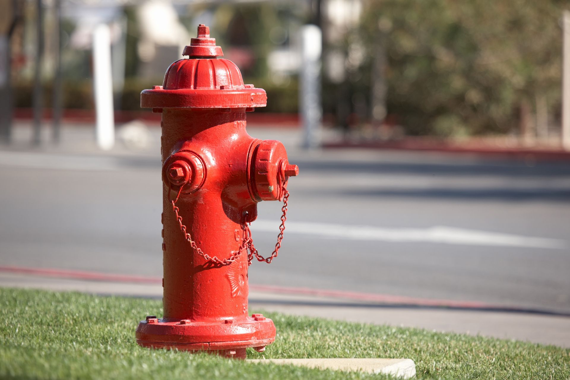 Red fire hydrant on a grassy curb beside a street