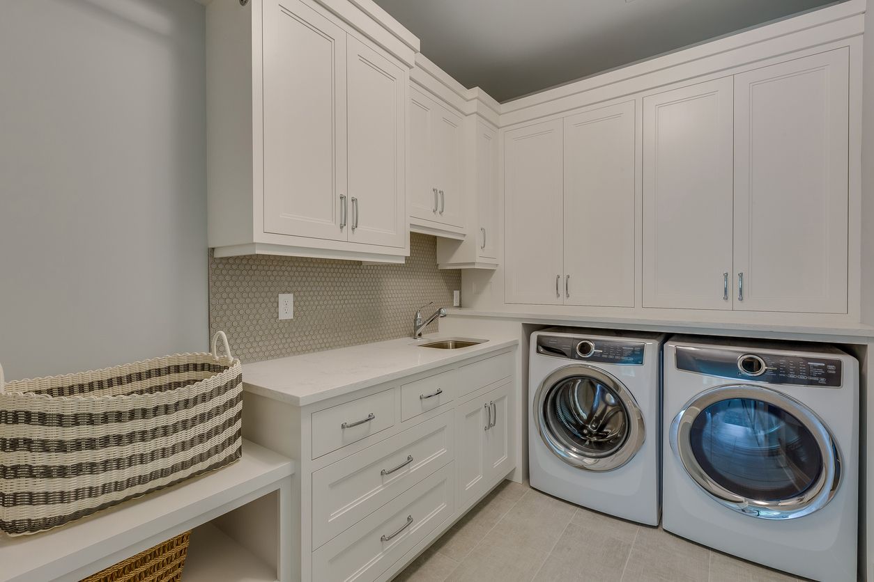 Laundry room with white cabinets, countertop, and a washer and dryer side by side.