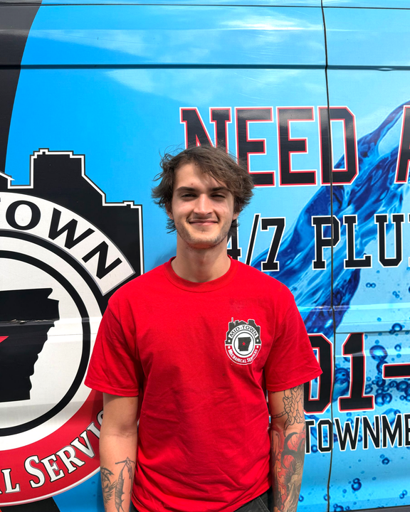 Smiling person in a red T-shirt standing before a blue mural with bold black lettering