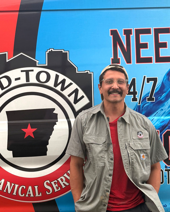 Man standing beside a colorful Mid-Town Mechanical Service van with skyline logo and red star emblem