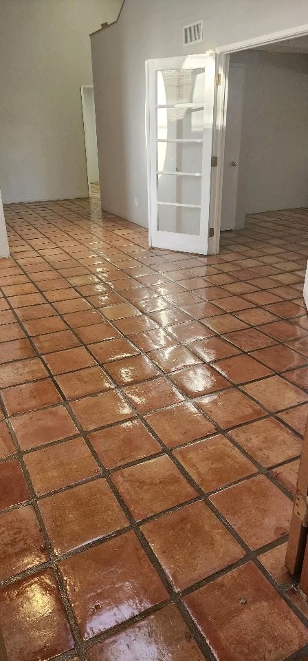 A large empty room with a tiled floor and a door.