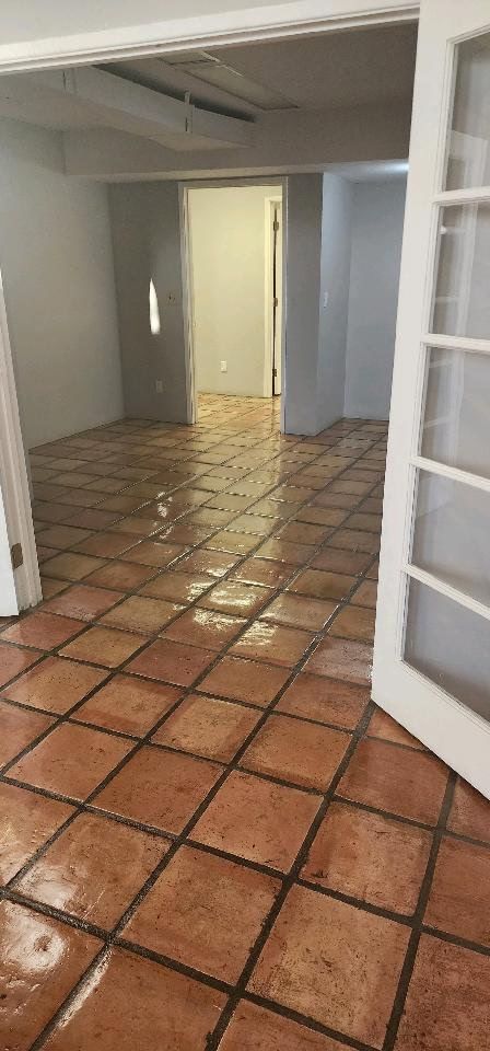 An empty room with a tiled floor and a white door.