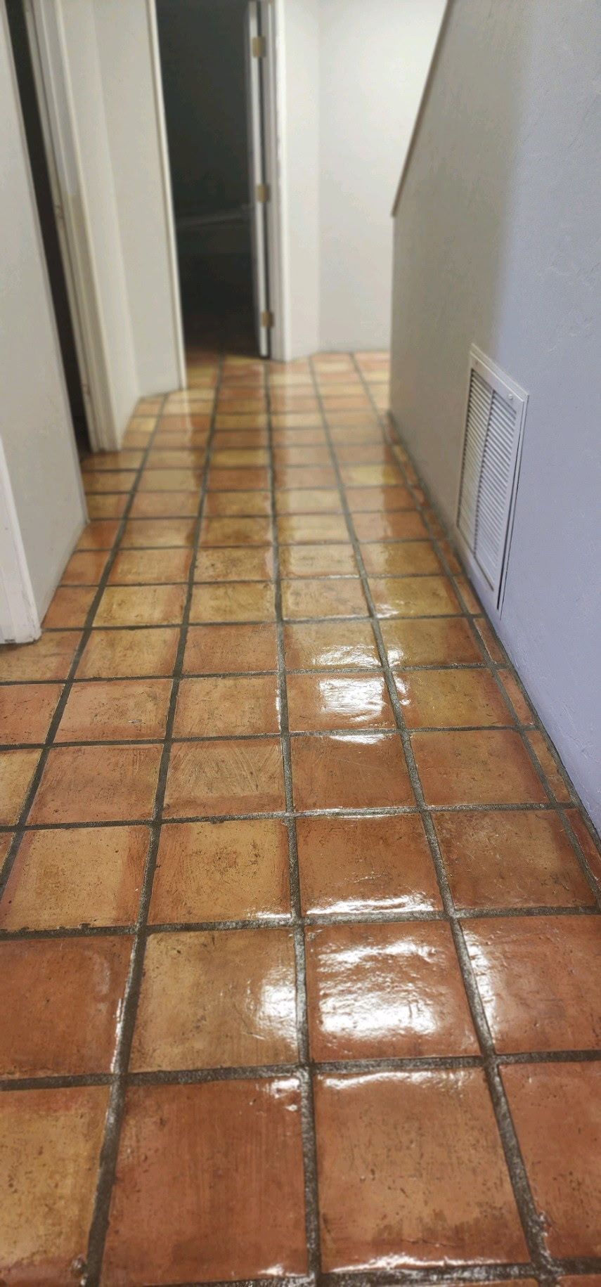 A hallway with tile floors and a white wall.