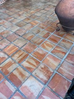 A person is standing on a tiled floor next to a pot.