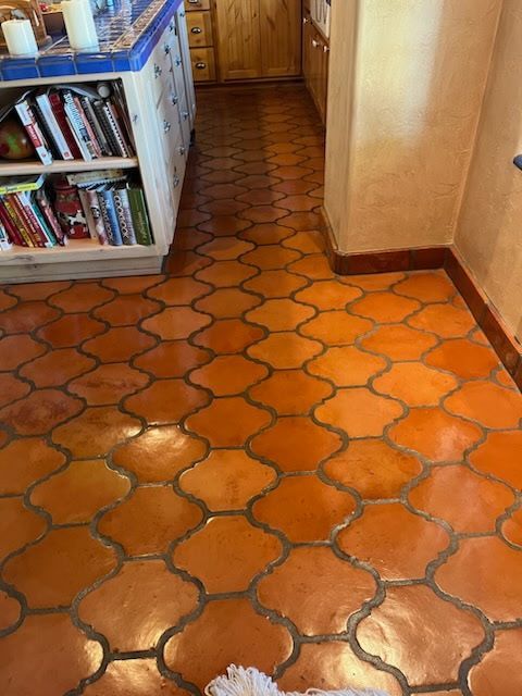 A dog is sitting on a tiled floor in a kitchen.