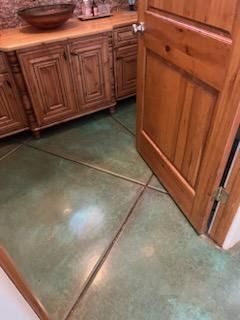 A bathroom with a green tile floor and wooden cabinets.