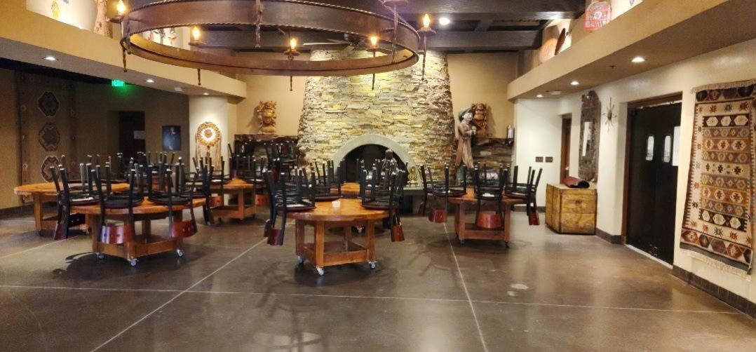 A large room with tables and chairs in it and a fireplace.