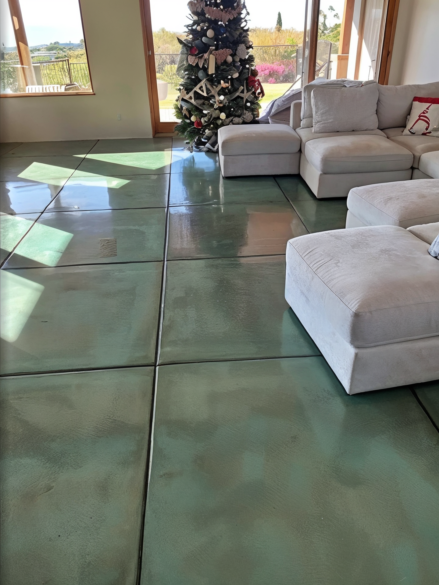 A living room with a couch , chairs , ottoman and a christmas tree.