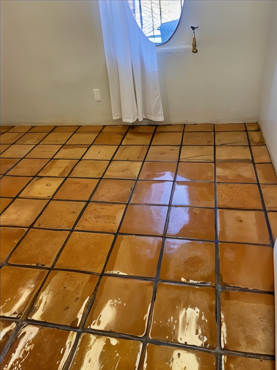 A bathroom with a tiled floor and a white shower curtain