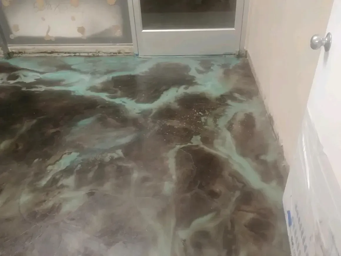 A concrete floor with a marble pattern and a door in the background.