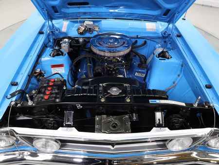 The engine of a blue car is shown with the hood open.