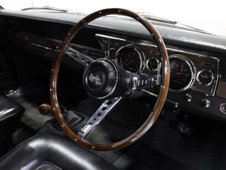 A close up of a car dashboard with a wooden steering wheel