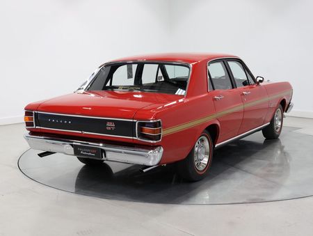 A red car is parked on a white surface in a showroom.