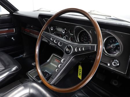 A close up of a car dashboard with a wooden steering wheel