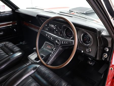 The interior of a red car with a wooden steering wheel