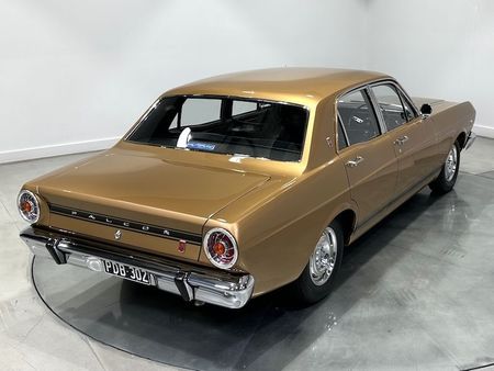 A gold ford falcon is parked in a garage.