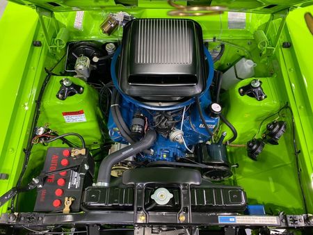 The engine of a green car is shown with the hood open.