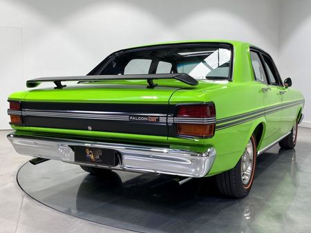 A green car with a spoiler on the back is parked in a garage.