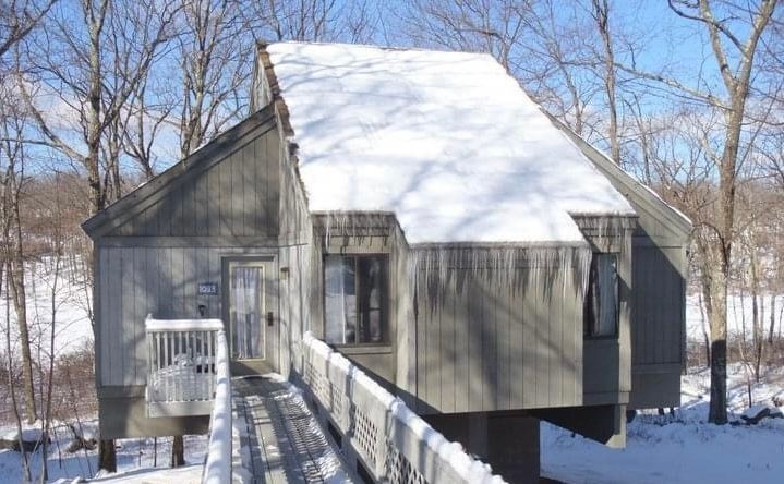 A house with snow on the roof and trees in the background