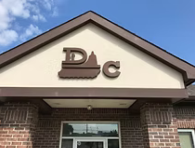 Brown and tan building facade with the letters "P D C" in a logo above the entrance.