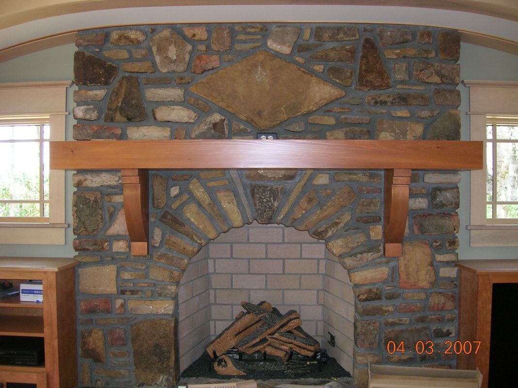Stone fireplace with wooden mantel and arched brick firebox, holding logs inside indoors