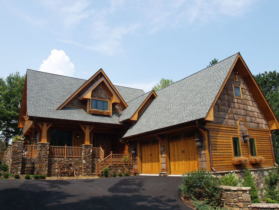 Rustic wooden cabin with stone accents and steep shingled roof under a clear blue sky