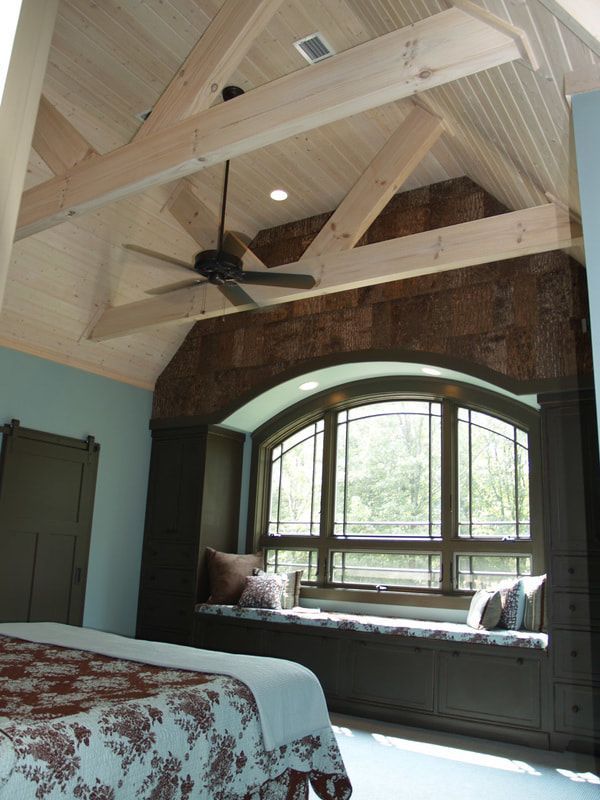 Bright bedroom with vaulted wooden ceiling, arched window seat, and bed in foreground