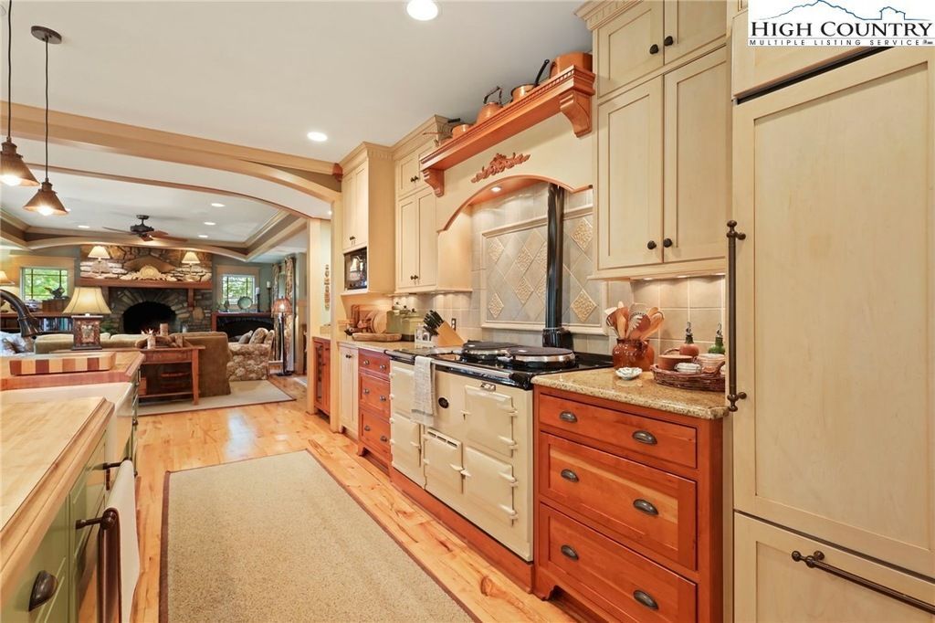 Warm rustic kitchen with cream cabinets, wood accents, island, and a stone range hood