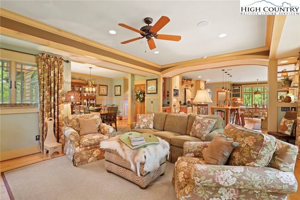Bright living room with floral sofas, tan walls, ceiling fan, and a large sliding glass door