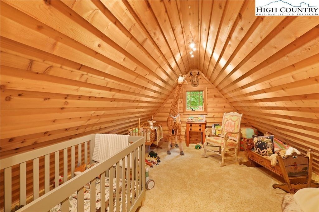 Warm wood-paneled loft with vaulted ceiling, railing, window seat, and rustic decor around a fireplace.