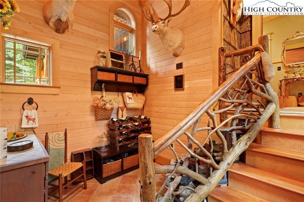 Rustic wooden interior with staircase, log railing, and wall shelves in a cozy cabin-like room