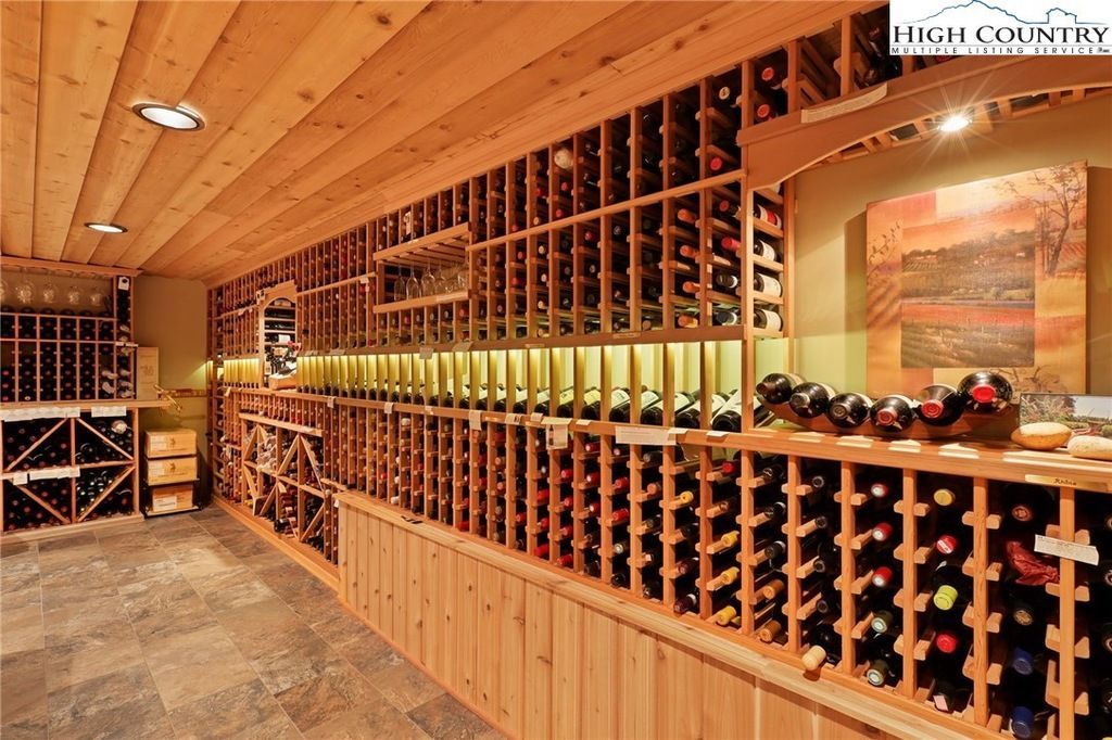 Wooden wine cellar with racks of wine bottles and stone floor lighting