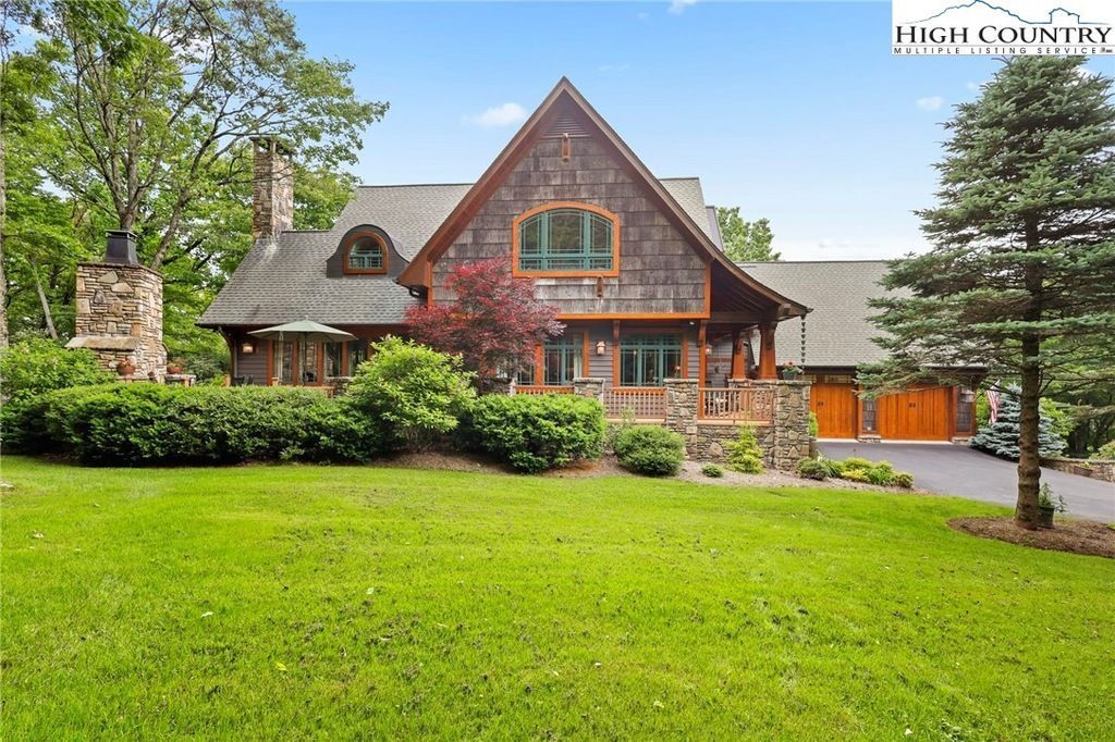 Large rustic house with a steep roof, stone accents, and a green lawn in front
