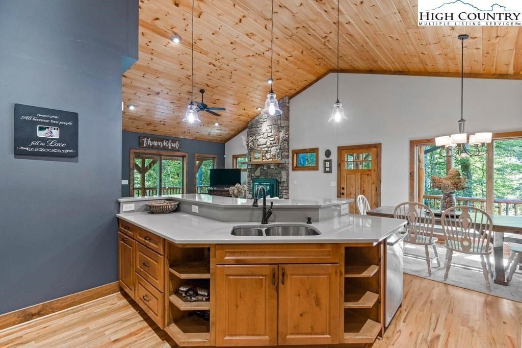 Modern kitchen with wood island, vaulted wood ceiling, and dining area by large windows
