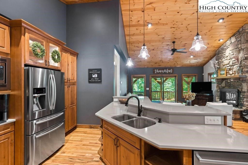 Modern kitchen with wood cabinets, black appliances, island sink, and pendant lights over hardwood floors
