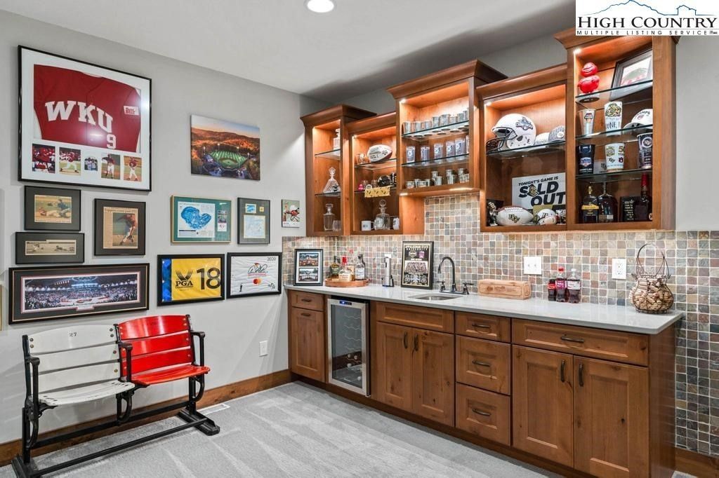 Wood-paneled trophy room with framed sports memorabilia, glass cabinets, and red chairs.