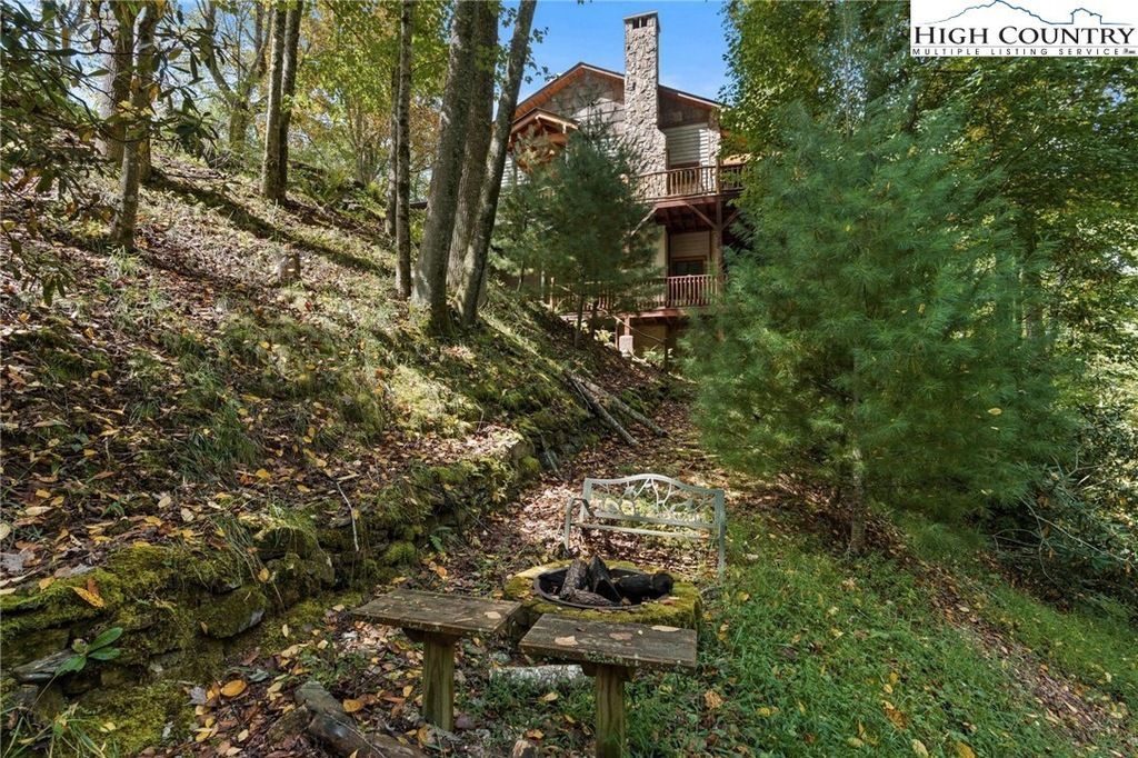 Stone steps lead up a wooded hillside to a rustic cabin with a chimney and arched roof.