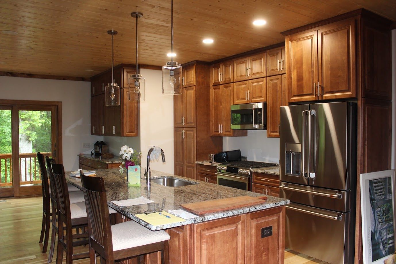 Modern kitchen with wooden cabinets, stainless steel appliances, granite island, and a breakfast bar