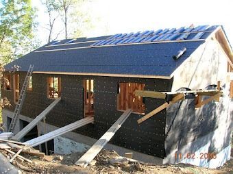 House under construction with brick walls, roof under renovation, and wooden support beams in front