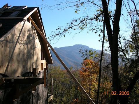 Cabin roof beside a mountain view with autumn trees and blue sky