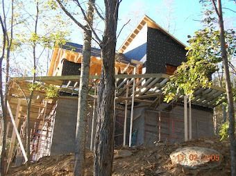 Partially built house with wooden scaffolding and exposed roof beams among trees