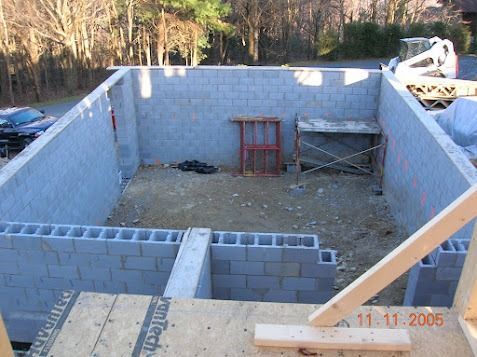 Partially built concrete block foundation with construction materials in a wooded area