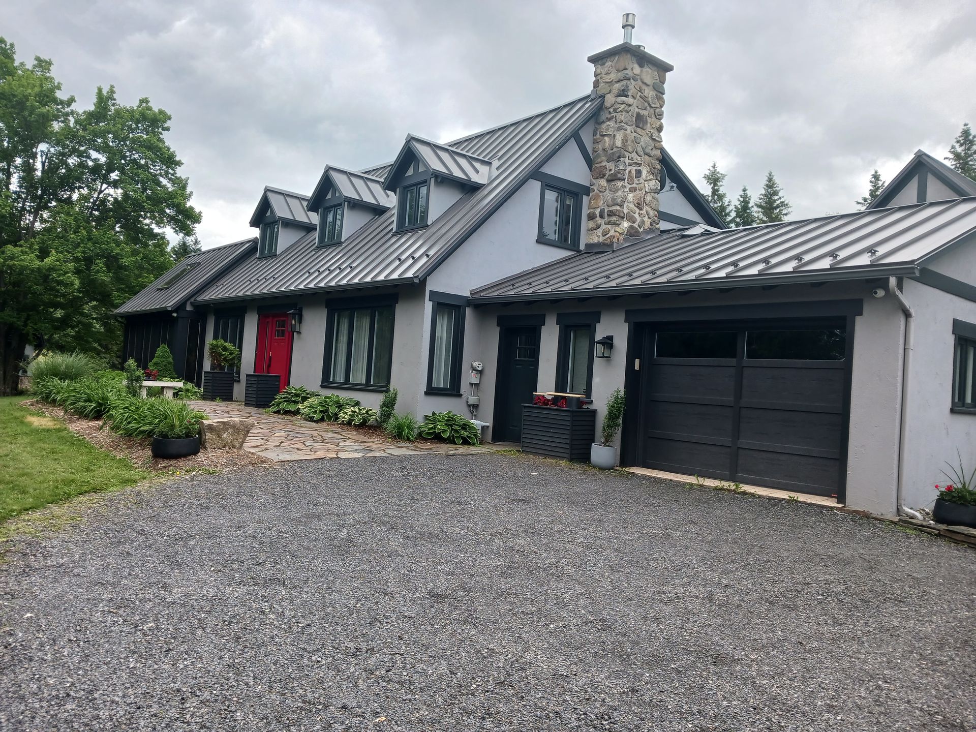 Une grande maison avec une porte de garage noire et une porte rouge