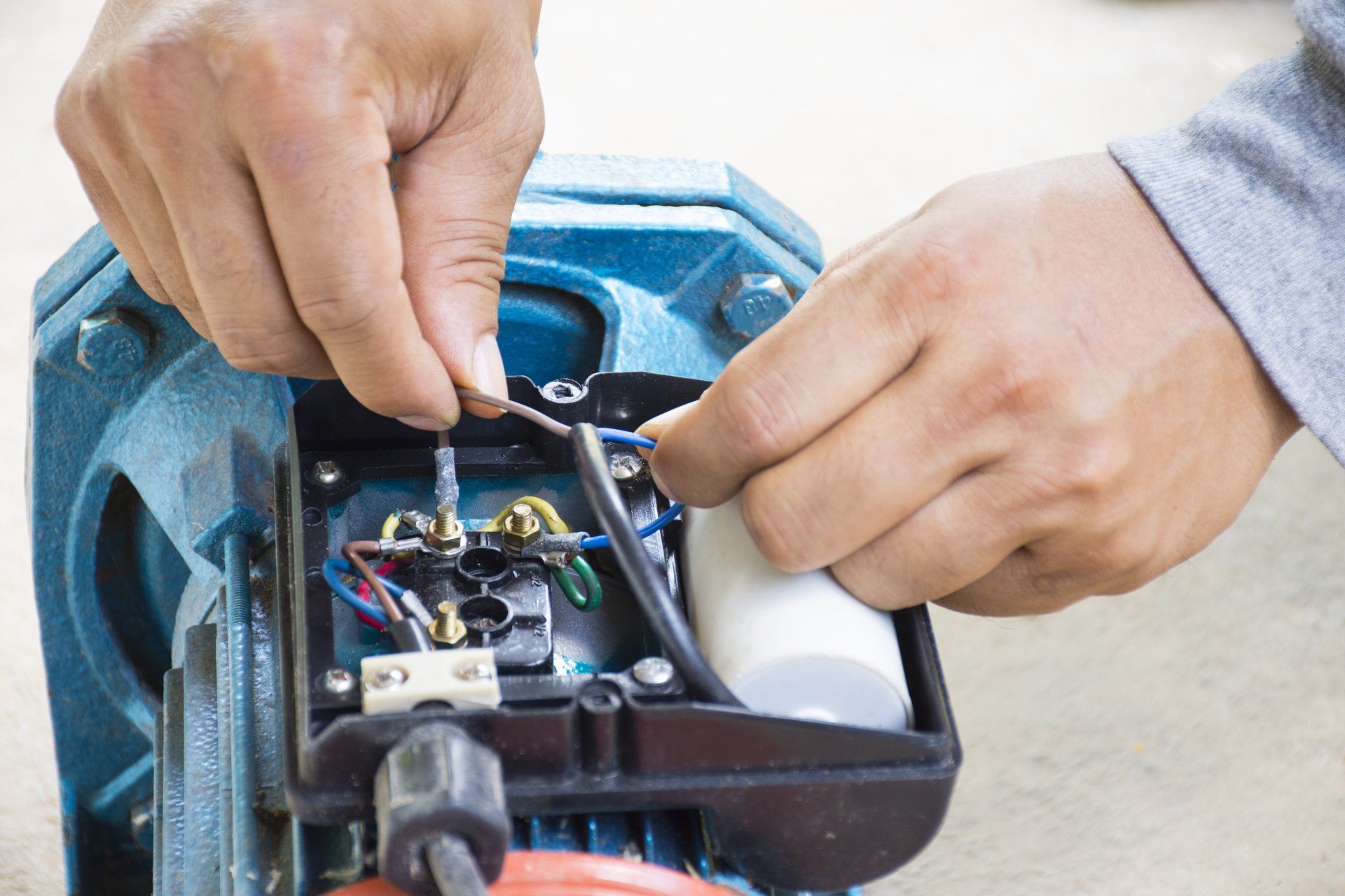 man's hands fixing blue electric motor