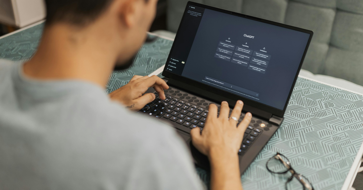 A person typing on a laptop that displays a tree diagram on its screen, positioned on a patterned table.