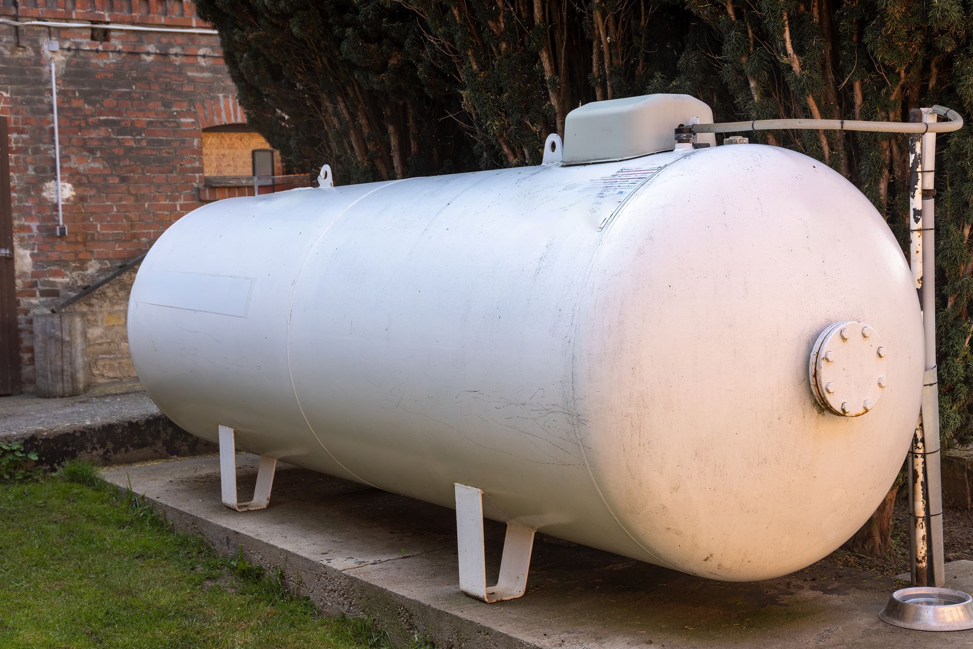 Two propane tanks are attached to a blue wooden wall.